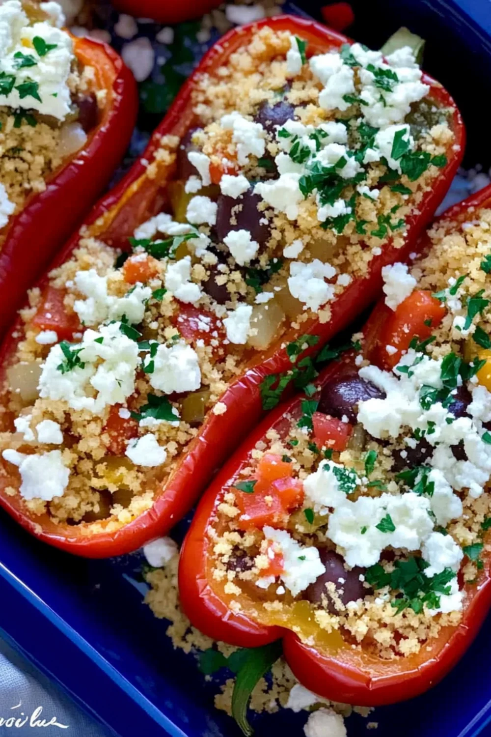Close-up of red bell peppers stuffed with a mixture of rice, vegetables, and herbs, garnished with fresh parsley.