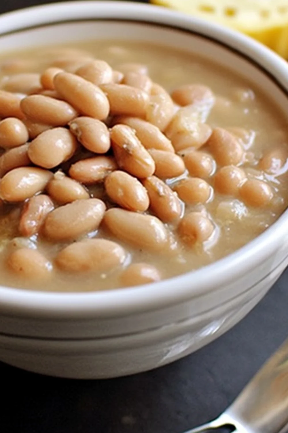 A bowl of Crockpot Great Northern Beans served warm in a white ceramic bowl, with creamy broth and tender beans.