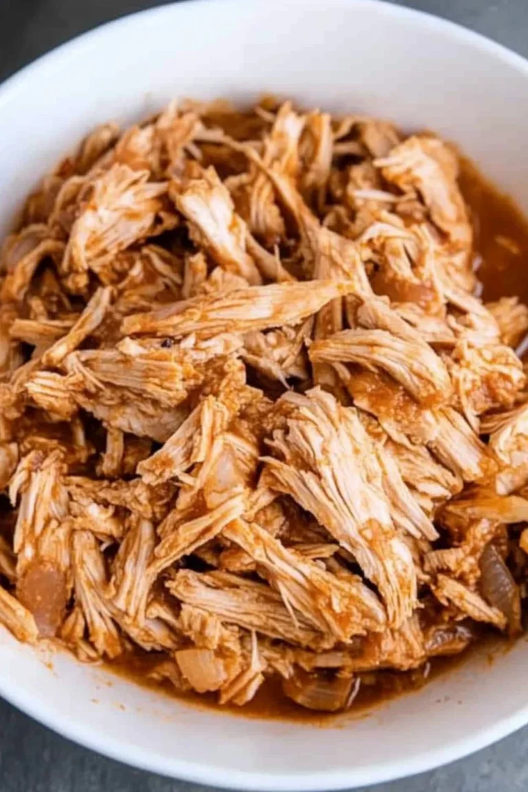 A bowl of tender, shredded Slow Cooker Mexican Chicken in a savory sauce, perfect for tacos or burritos.