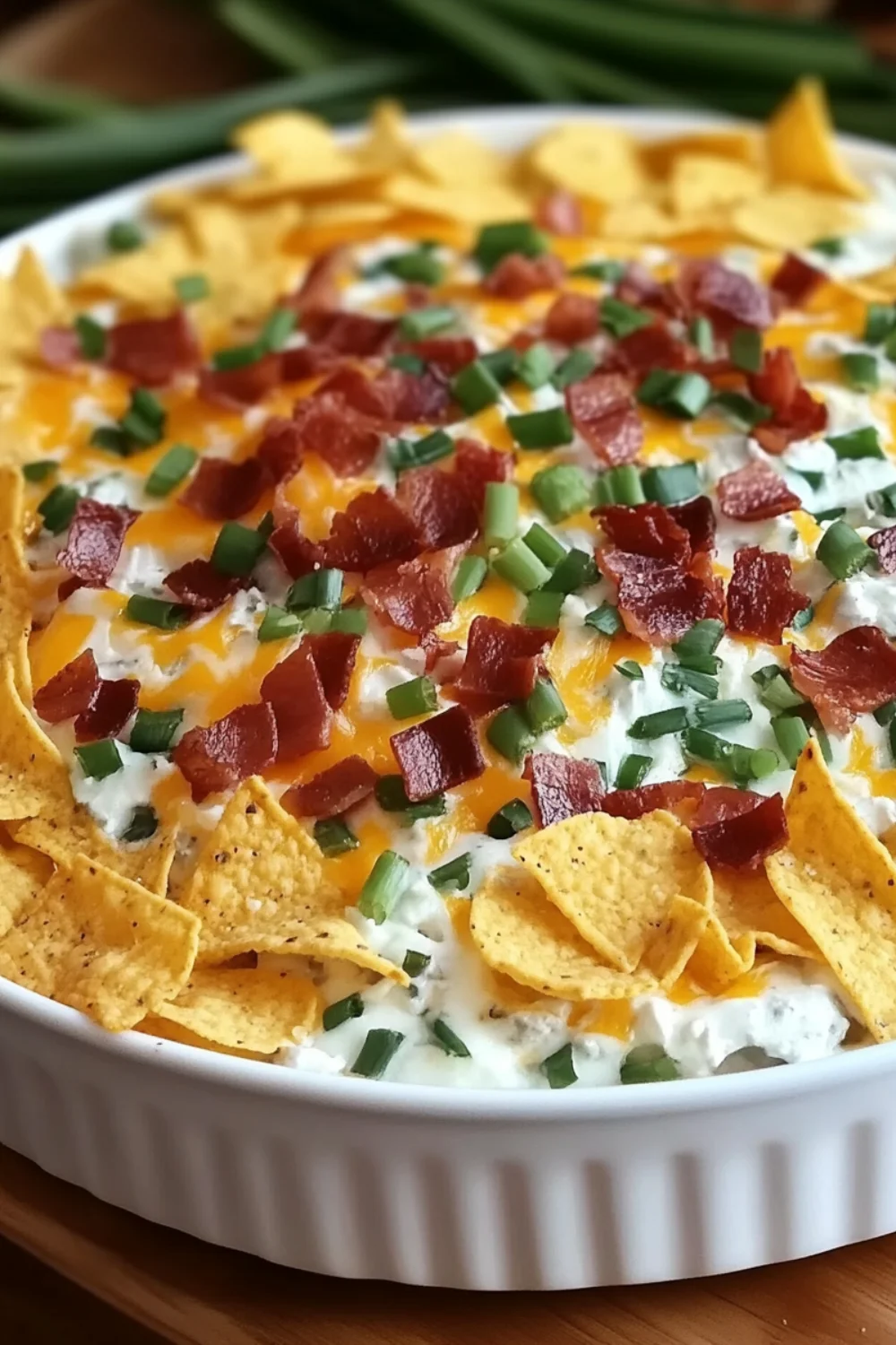 A creamy dip with chunks of corn and herbs, served in a white bowl with crispy crackers for dipping.
