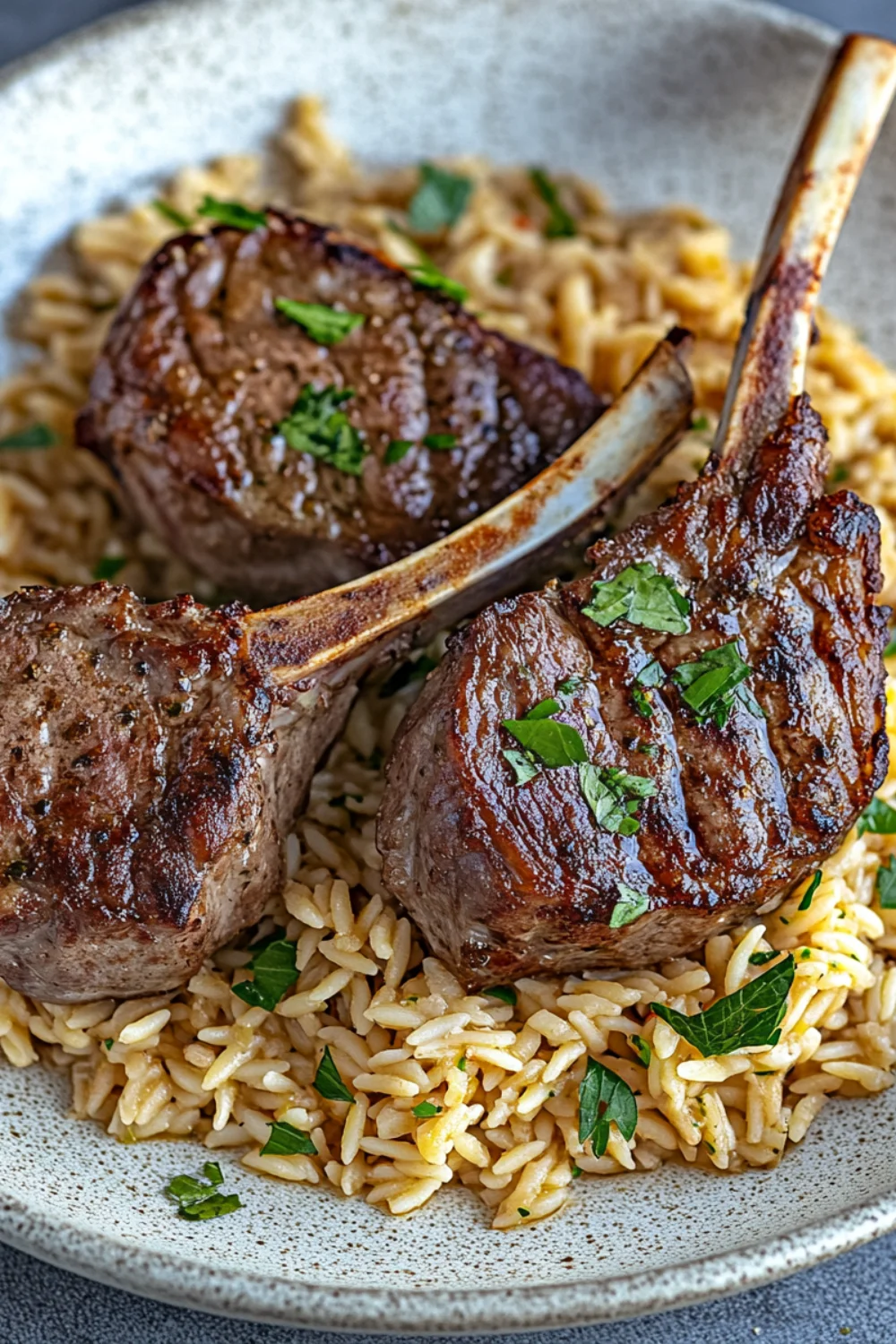 Sliced herby lamb resting on a bed of orzo pasta, garnished with fresh rosemary sprigs.