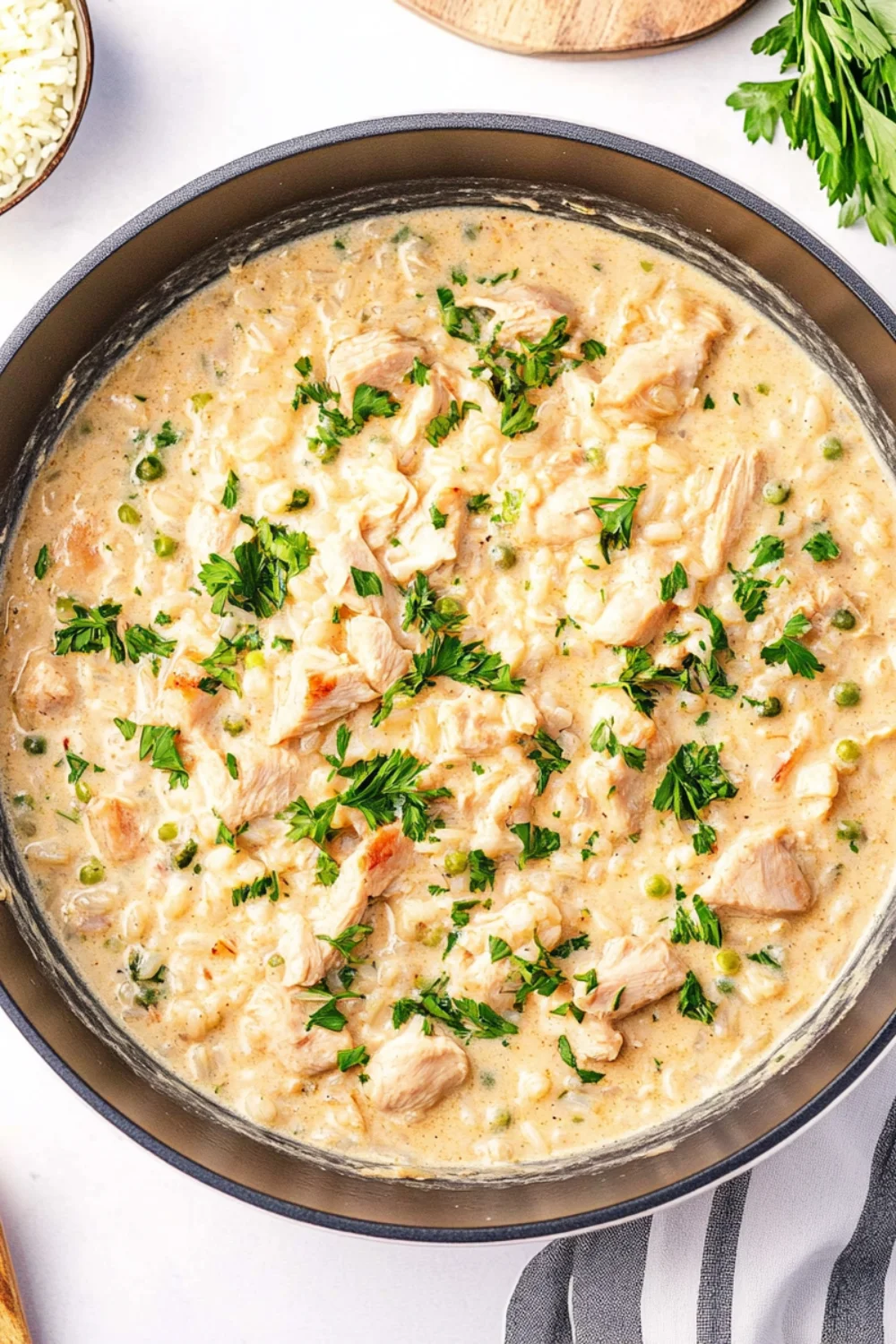 Creamy chicken and rice skillet dish with chunks of tender chicken, green peas, and fresh parsley in a rich sauce.